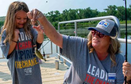 A woman holds a fish on a line with the child who caught it