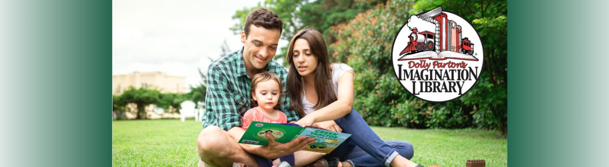 A father, mother and toddler sit in a park reading a book. Dolly Parton's Imagination Library logo sits in the upper left. 